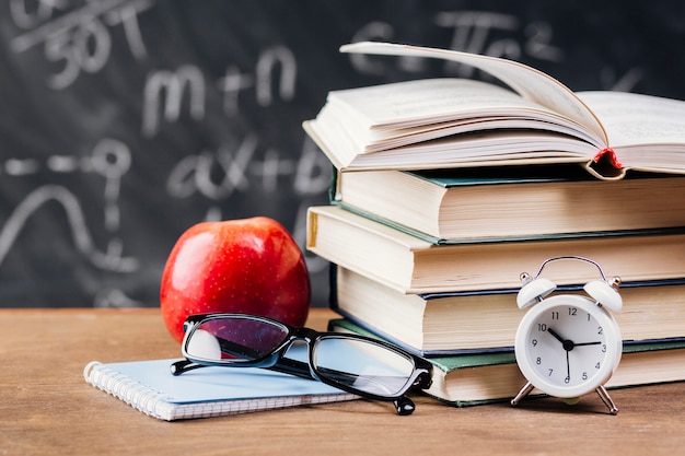 Relógio à frente dos livros didáticos na mesa do professor