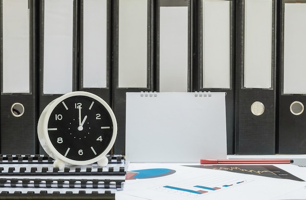 Relógio branco closeup para decorar na 1 h secretária de oficial com papel de trabalho
