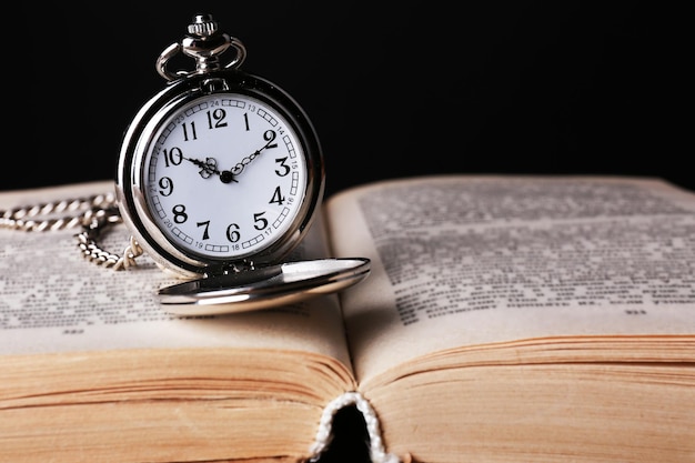 Relógio de bolso de prata e livro na mesa de madeira