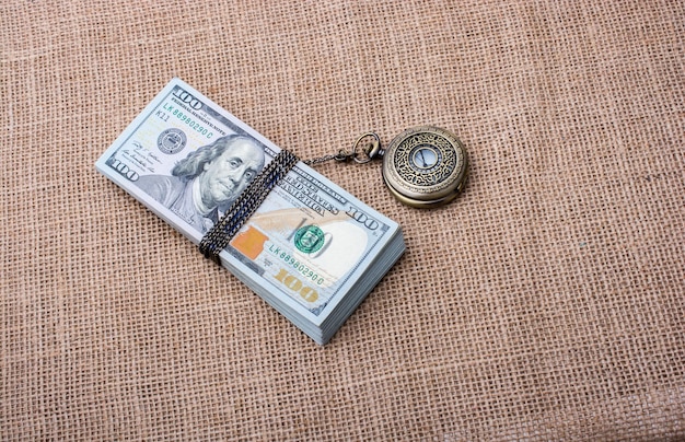 Foto relógio de bolso enrolado em dólares americanos