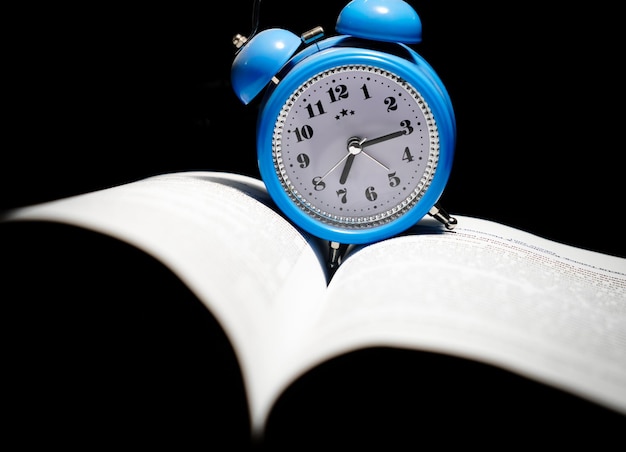 Foto relógio de despertador azul em uma página do livro hora de estudar ilustração
