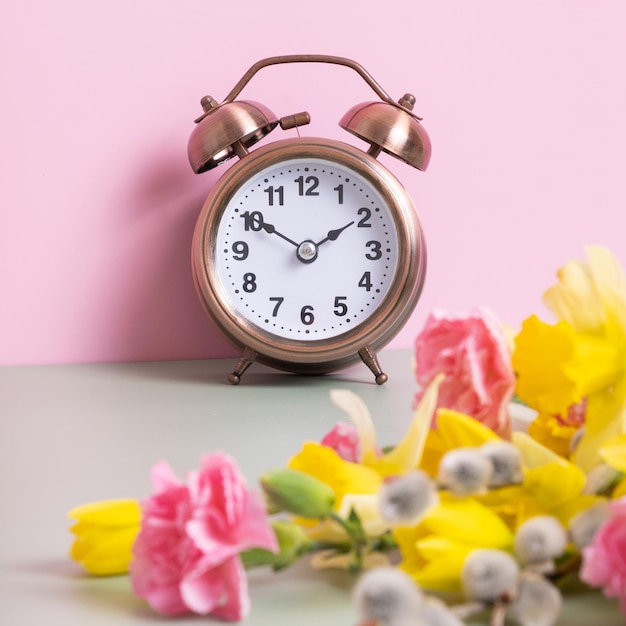 Relógio despertador com flores de primavera Horário de primavera conceito de horário de verão primavera para a frente
