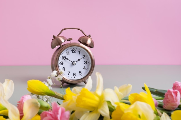 Relógio despertador com flores em fundo rosa Horário de primavera Horário de verão Primavera para a frente