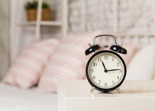 Relógio despertador preto perto da cama