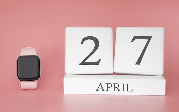 Relógio moderno com calendário de cubo e data 27 de abril em fundo rosa. férias de primavera conceito.