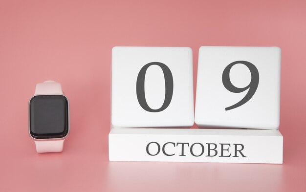 Relógio moderno com calendário de cubo e data 9 de outubro em fundo rosa