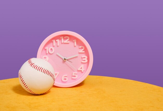 Foto relógio redondo rosa e basebol de couro seu tempo de treinamento e esportes copiar espaço para texto