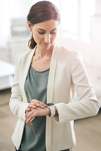 Relógios inteligentes para mulheres de negócios inteligentes Foto de uma jovem empresária em um escritório usando um smartwatch