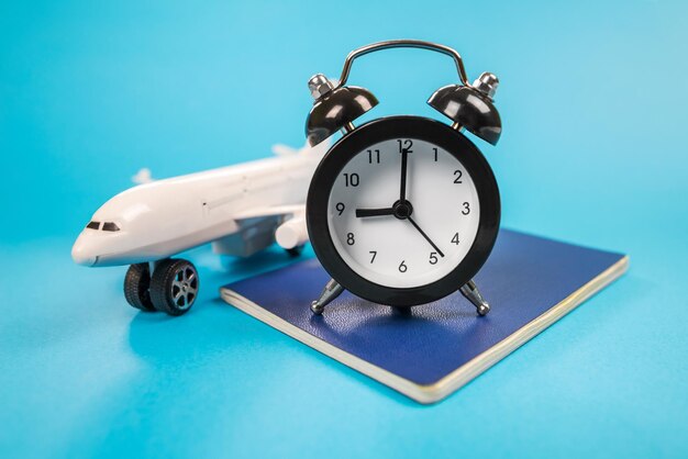 Foto reloj de alarma con un avión de juguete pasaportes en azul hora de vuelo