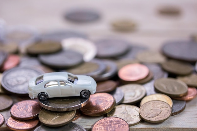 Reloj de alarma de coche de juguete y pilas de monedas en el fondo de la mesa de madera