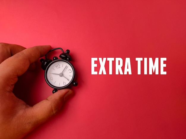 Reloj de alarma de mano con la palabra Tiempo Extra en un fondo rojo