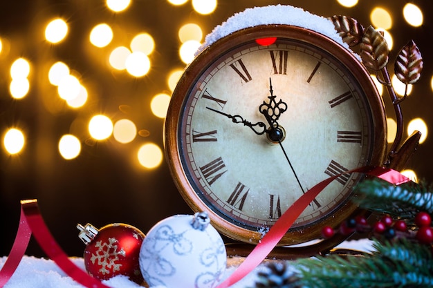 Foto reloj de año nuevo y adornos cubiertos con luces tarjeta de navidad