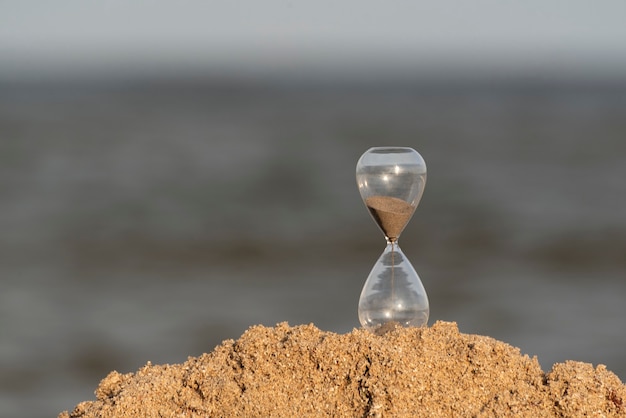 Reloj de arena en la arena del mar. Concepto de tiempo.