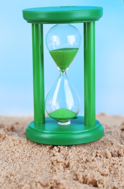 Reloj de arena en arena sobre el fondo del cielo azul