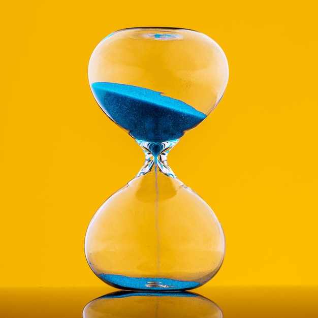 Reloj de arena azul sobre fondo amarillo.