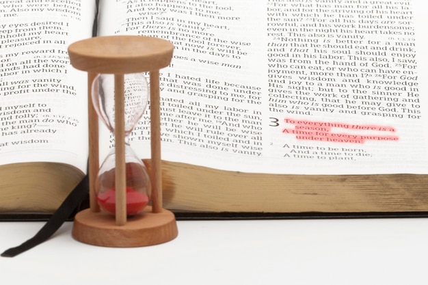 Reloj de arena y Biblia abierta en el libro de Eclesiastes