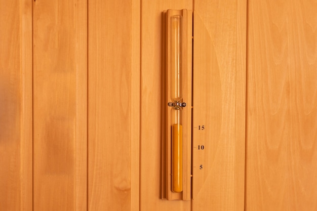 Foto reloj de arena colgado en la pared de madera de la sauna. temporizador de reloj de arena.