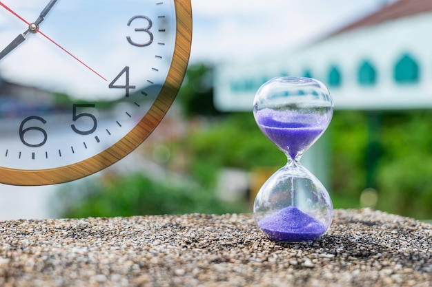 Foto el reloj de arena estaba sobre la superficie rocosa áspera cerca del canal de la marea creciente. muestra que el agua que fluye nunca retrocede en el tiempo.