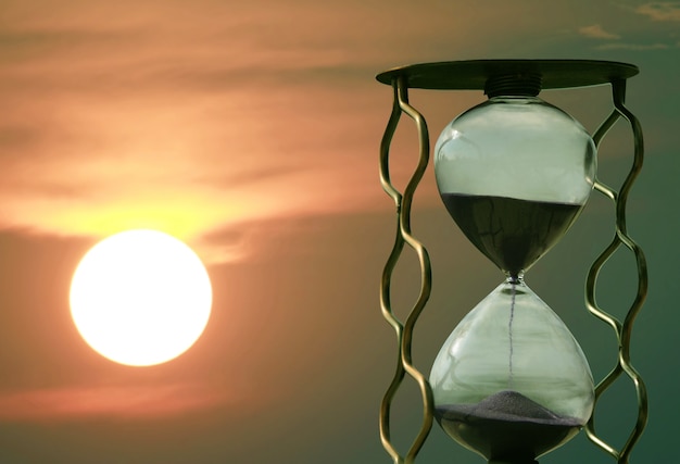 Reloj de arena en el fondo de una puesta de sol. paso rápido del tiempo