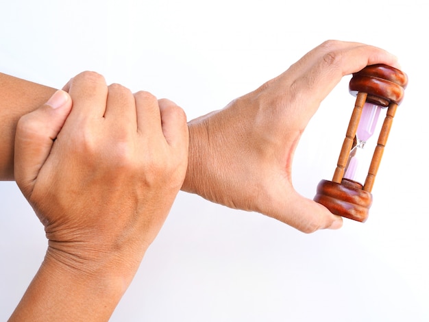 Reloj de arena en la mano, tiempo con cuidado de la salud y ejercicio, dolor en los brazos, huesos y músculos de la muñeca, aislado en la superficie blanca.