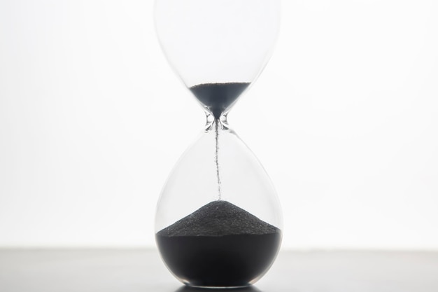 Reloj de arena sobre un fondo claro. El tiempo es dinero. Soluciones de negocio en el tiempo.
