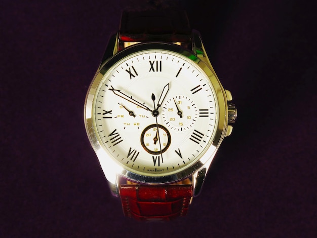 Un reloj con banda roja y carátula blanca dice que son las 10:00.