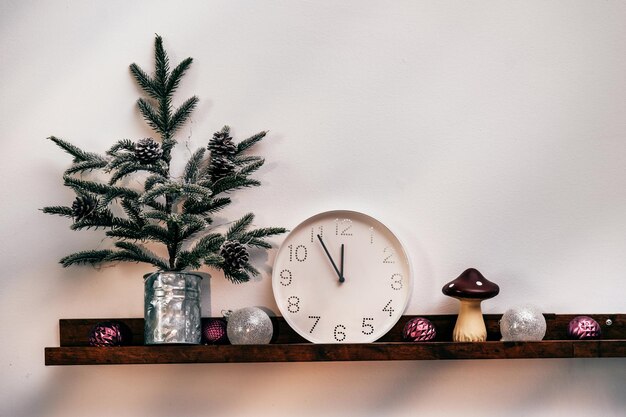 Reloj blanco del árbol de navidad y decoraciones delante de la pared de madera