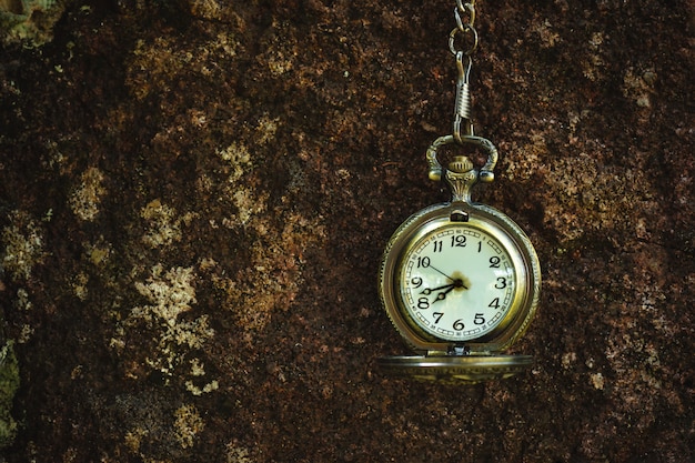 Reloj de bolsillo antiguo vintage colgado en la pared de roca