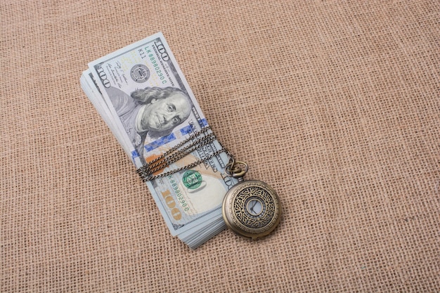 Reloj de bolsillo envuelto en dólares estadounidenses
