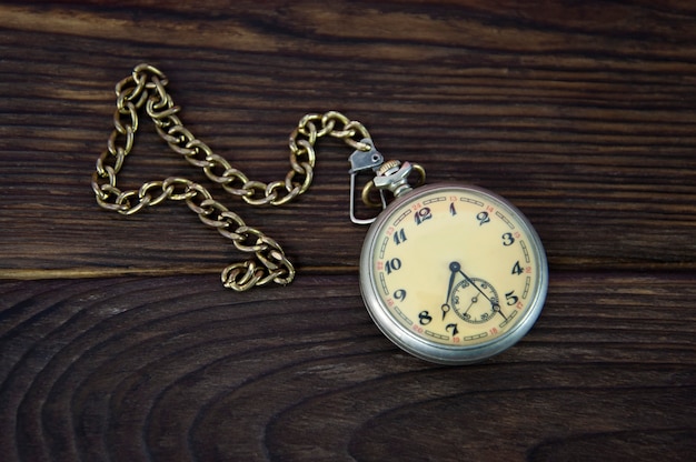 Foto reloj de bolsillo con gorra sobre una superficie de madera.