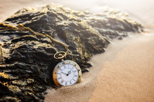 Reloj de bolsillo vintage en la playa de arena dorada