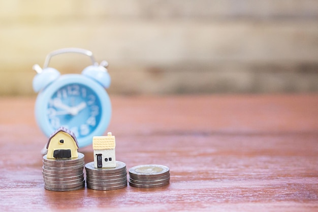 Reloj Coinsalram y juguete de la casa sobre fondo de mesa de madera