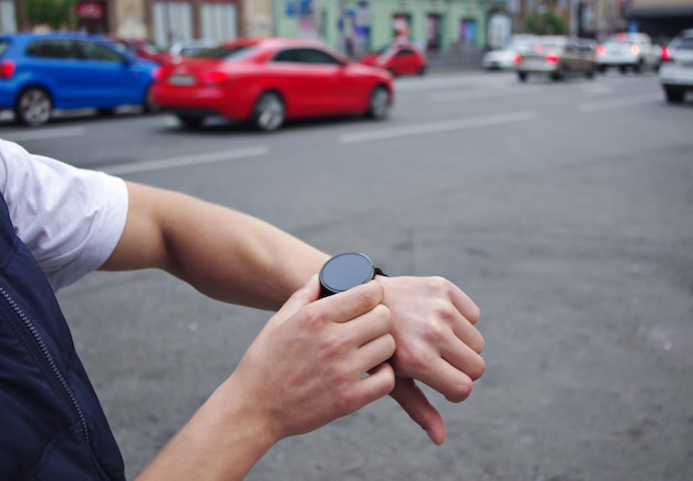 Reloj deportivo para correr en la mano de un hombre en el fondo de la ciudad y los autos