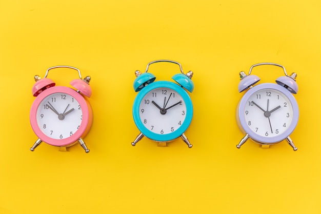 Reloj despertador clásico de tres timbres gemelos de diseño simplemente minimalista aislado en amarillo