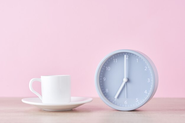 Reloj despertador gris clásico y taza de café con leche