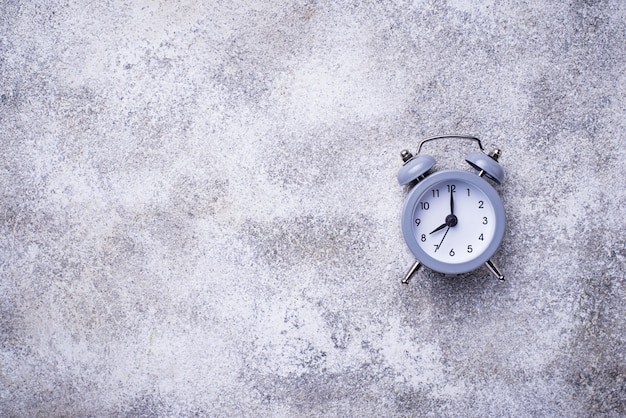 Reloj despertador gris vintage en mesa de concreto