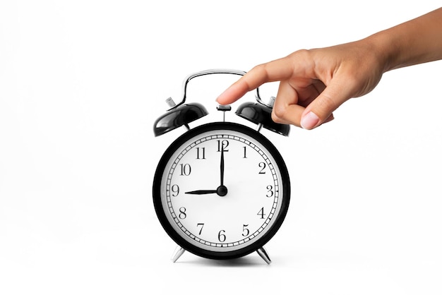 Reloj despertador negro Mano femenina apagando el despertador que suena sobre fondo blanco a las 9 en punto
