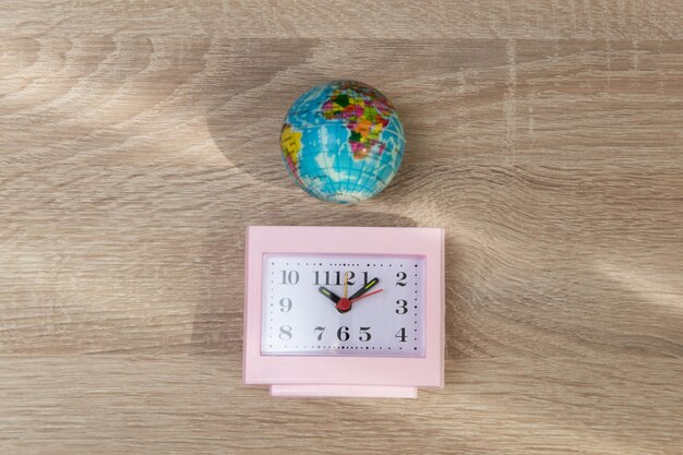 Foto reloj de despertador rosa cuadrado con globo sobre una mesa de madera