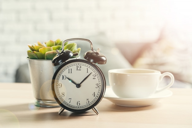 Reloj despertador vintage clásico y taza de café sobre fondo de madera