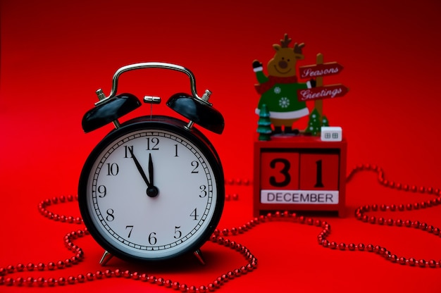 Un reloj despertador vintage negro y un calendario de Navidad rojo están aislados en un re