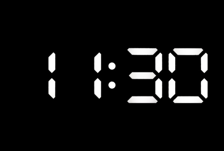 Foto reloj digital led blanco real sobre un fondo negro que muestra la hora 1130.