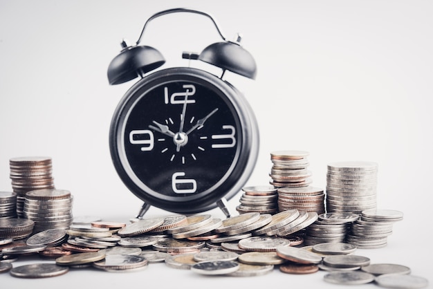 Foto reloj e hileras de monedas por el tiempo de las finanzas y el concepto de negocio