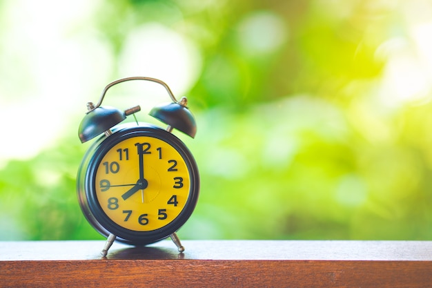 Reloj de escritorio negro con pantalla amarilla en la mesa de madera