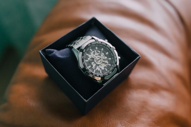 Un reloj está sentado en una caja en una superficie marrón