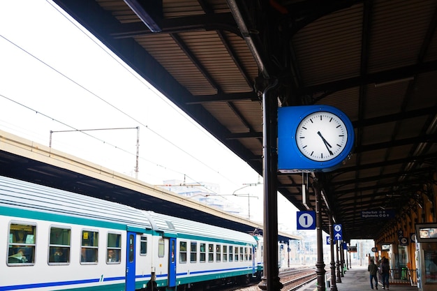 Foto reloj exterior en plataforma ferroviaria y tren.