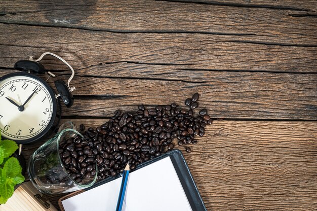 Reloj de granos de café de Bloc de notas colocado en una vista superior de la mesa de madera