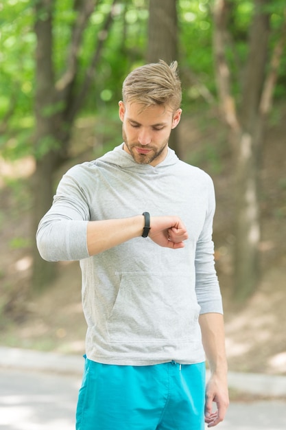 Reloj ideal para un estilo de vida activo El hombre atlético verifica el pulso con el reloj Un atleta guapo usa un reloj inteligente durante el entrenamiento Seguimiento del estado físico Seguimiento del entrenamiento deportivo con reloj Tecnología y deporte