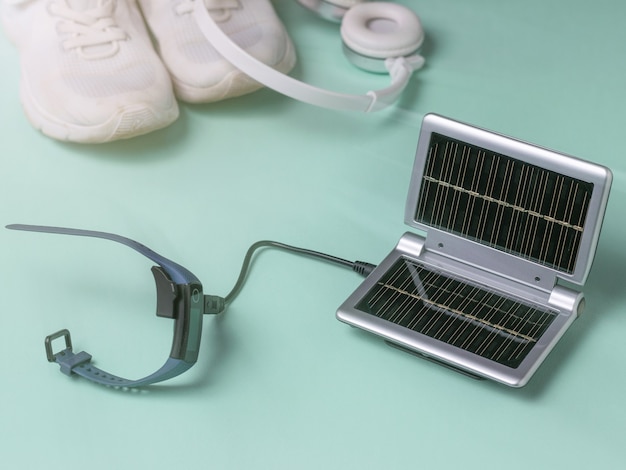 El reloj inteligente se carga desde un cargador portátil en el fondo de zapatillas y auriculares. Uso de energía solar. Tecnología del futuro.