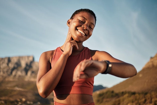 Reloj inteligente de frecuencia cardíaca y montaña con una mujer negra corriendo para el seguimiento de la actividad física cardio y monitorear los objetivos Deportes de tiempo y seguimiento de ejercicios con una corredora comprobando el progreso de la tecnología portátil