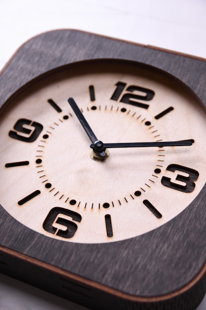 Reloj de madera hecho a mano en mesa de madera. De cerca.